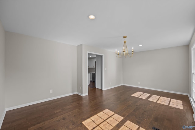 empty room with baseboards, an inviting chandelier, recessed lighting, and dark wood finished floors