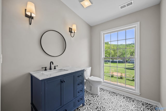 bathroom with toilet, vanity, visible vents, and plenty of natural light