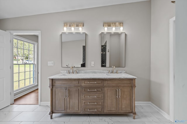 bathroom with double vanity, marble finish floor, baseboards, and a sink