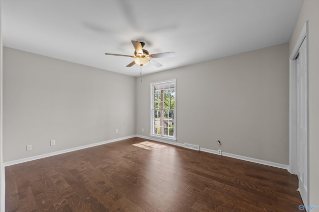 empty room featuring dark wood finished floors, baseboards, a ceiling fan, and visible vents