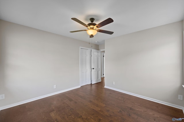 empty room featuring a ceiling fan, baseboards, and dark wood-style flooring