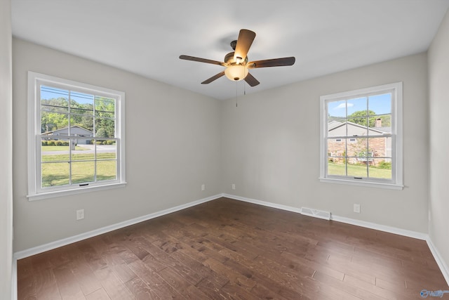 spare room with a healthy amount of sunlight, dark wood-style flooring, and visible vents