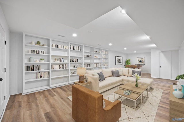 living area featuring visible vents, light wood-style flooring, built in features, and recessed lighting