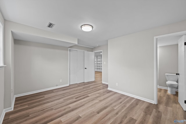 unfurnished bedroom featuring baseboards, wood finished floors, visible vents, and a closet