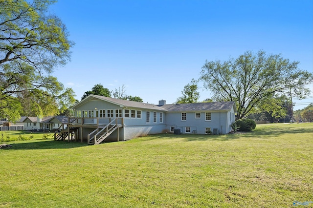 rear view of property featuring a lawn, a chimney, stairway, and a deck