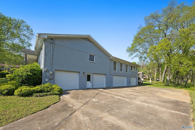 view of side of home with a garage, brick siding, and concrete driveway