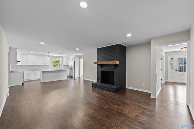 unfurnished living room with recessed lighting, baseboards, and dark wood-style flooring
