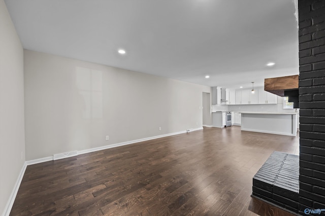 unfurnished living room featuring baseboards, visible vents, recessed lighting, and dark wood-type flooring