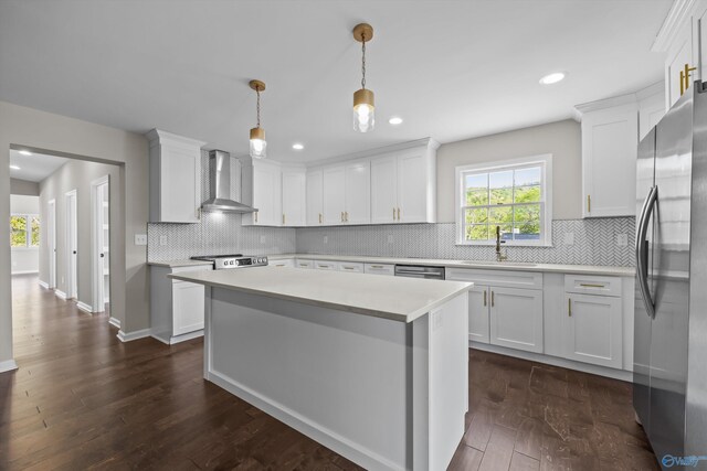 kitchen featuring a sink, light countertops, dark wood finished floors, wall chimney exhaust hood, and appliances with stainless steel finishes