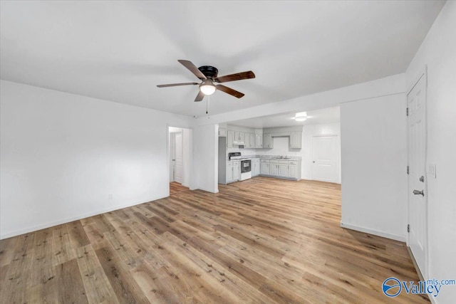 unfurnished living room with sink, light wood-type flooring, and ceiling fan