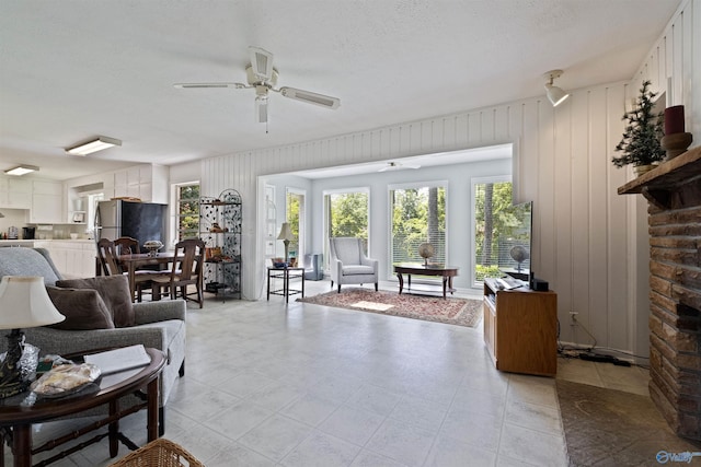 living room with ceiling fan and a textured ceiling