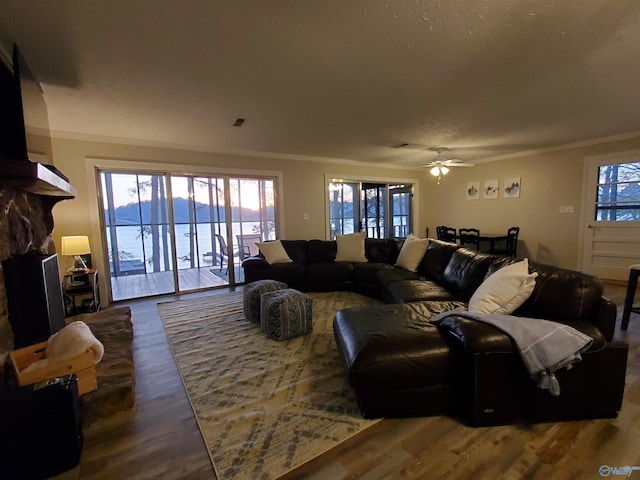 living room featuring crown molding, a water view, ceiling fan, a fireplace, and hardwood / wood-style floors