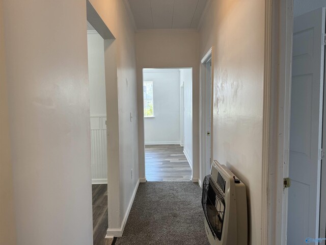 hall featuring ornamental molding, heating unit, and dark carpet