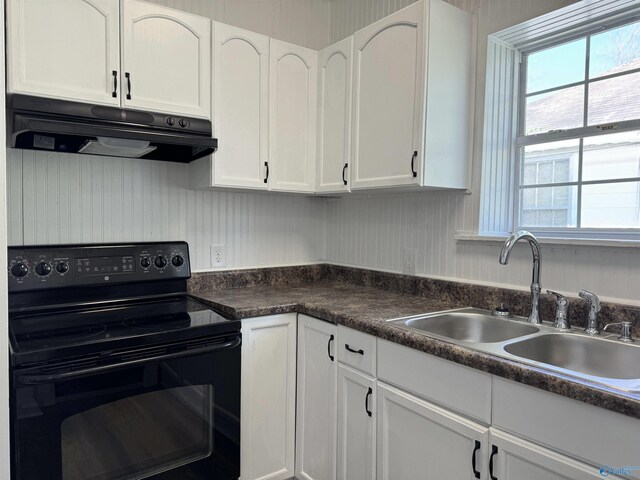 kitchen featuring black range with electric stovetop, a healthy amount of sunlight, and white cabinetry