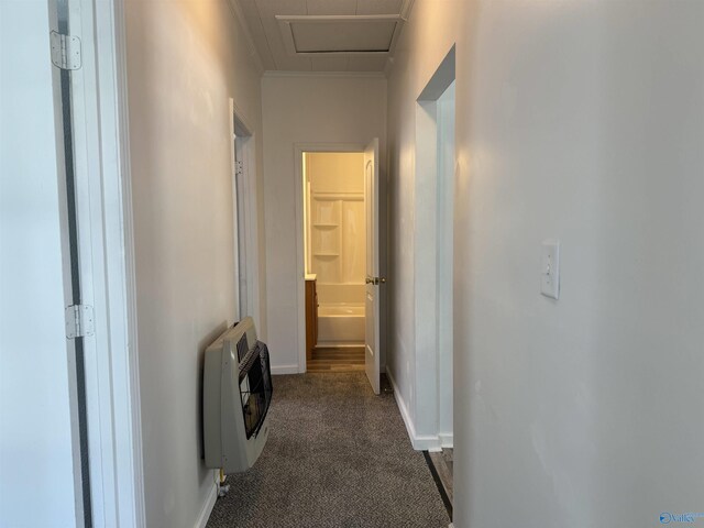 corridor with crown molding, dark carpet, and heating unit