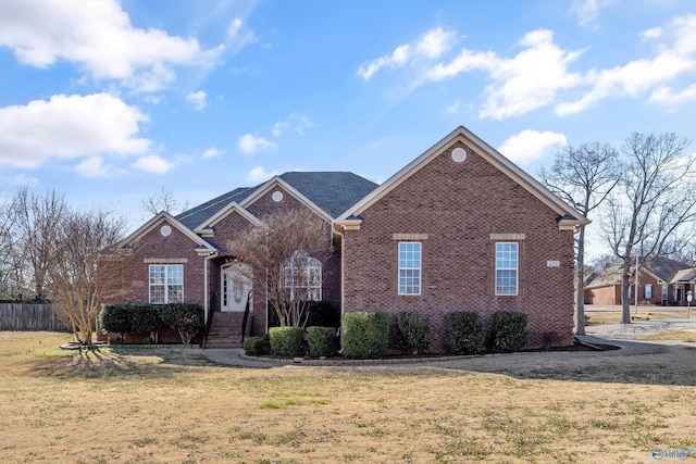 ranch-style house featuring a front yard, fence, and brick siding