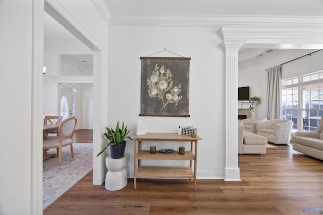 hallway featuring ornate columns, crown molding, baseboards, and wood finished floors