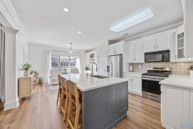 kitchen with ornamental molding, a sink, white cabinetry, stainless steel appliances, and light countertops