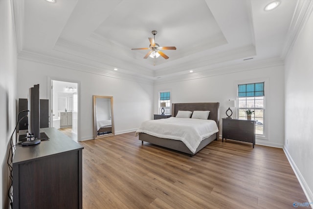 bedroom featuring a raised ceiling, light wood-style flooring, multiple windows, and crown molding