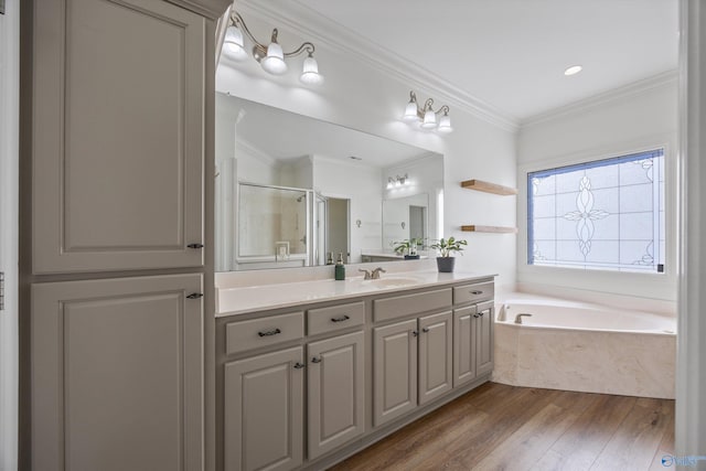 full bath featuring vanity, wood finished floors, ornamental molding, a garden tub, and a shower with door