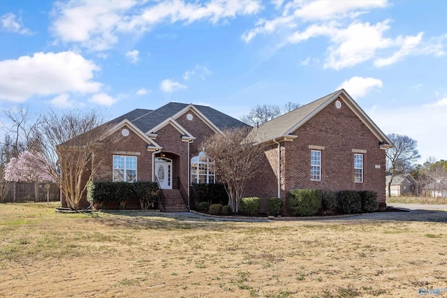 view of front of house with brick siding, a front yard, and fence