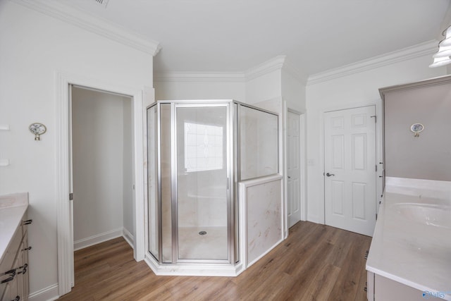 bathroom with vanity, a shower stall, wood finished floors, and crown molding