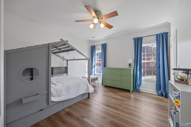 bedroom featuring ornamental molding, baseboards, a ceiling fan, and wood finished floors