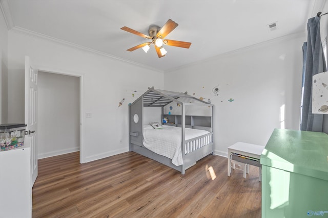 bedroom featuring visible vents, crown molding, baseboards, and wood finished floors