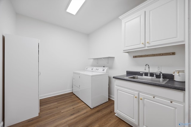 washroom featuring baseboards, washing machine and dryer, wood finished floors, cabinet space, and a sink