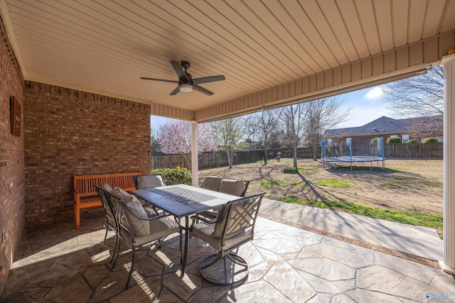 view of patio / terrace featuring outdoor dining space, a trampoline, a fenced backyard, and ceiling fan