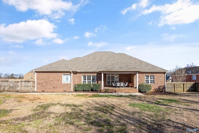 back of property featuring a gate, fence, a shingled roof, a patio area, and brick siding