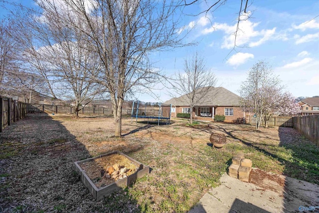 view of yard featuring a fenced backyard, a vegetable garden, and a trampoline