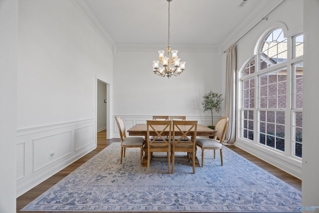 dining area featuring dark wood finished floors, ornamental molding, and a chandelier