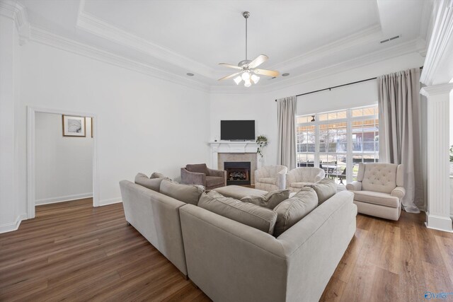 living area with a tray ceiling, wood finished floors, and a tile fireplace