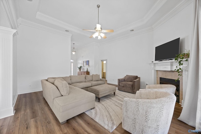 living room featuring ceiling fan, wood finished floors, ornamental molding, and a tile fireplace