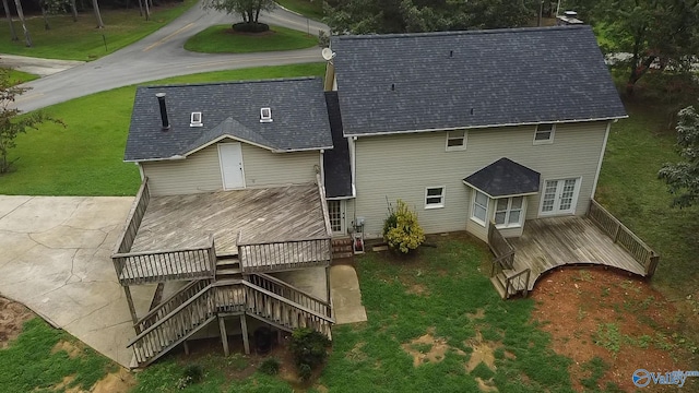 rear view of property featuring a wooden deck, a lawn, and a patio