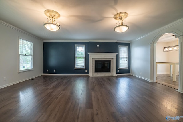 unfurnished living room featuring crown molding, a fireplace, dark hardwood / wood-style floors, and decorative columns