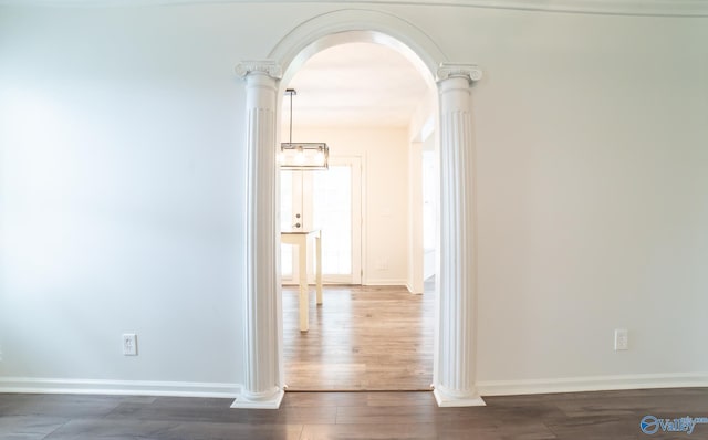 corridor featuring decorative columns and dark wood-type flooring