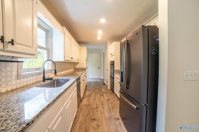 kitchen featuring white cabinetry, sink, backsplash, light stone counters, and stainless steel appliances