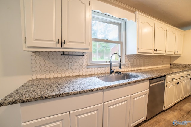 kitchen with light stone counters, dishwasher, sink, and white cabinets