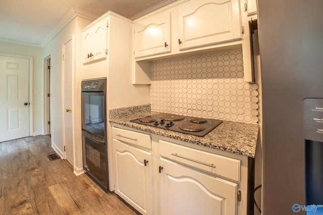 kitchen with white cabinetry, wood-type flooring, dark stone countertops, decorative backsplash, and black appliances