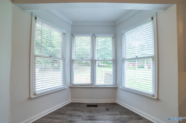 empty room featuring crown molding, dark hardwood / wood-style floors, and a healthy amount of sunlight