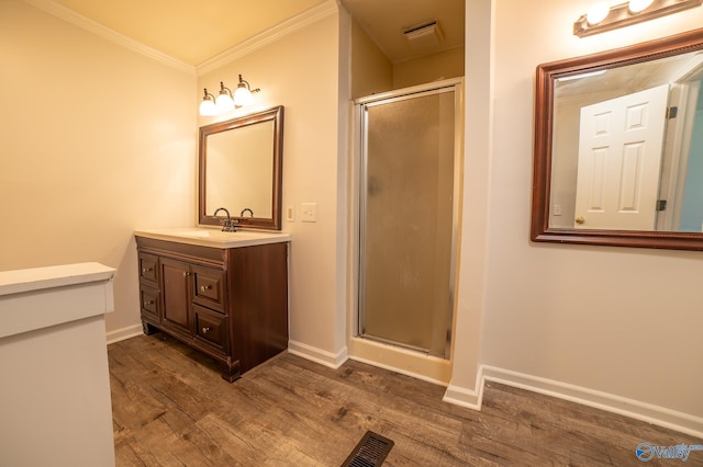 bathroom featuring wood-type flooring, ornamental molding, vanity, and walk in shower