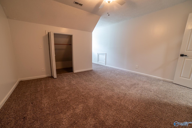 interior space featuring vaulted ceiling, carpet floors, ceiling fan, and a textured ceiling