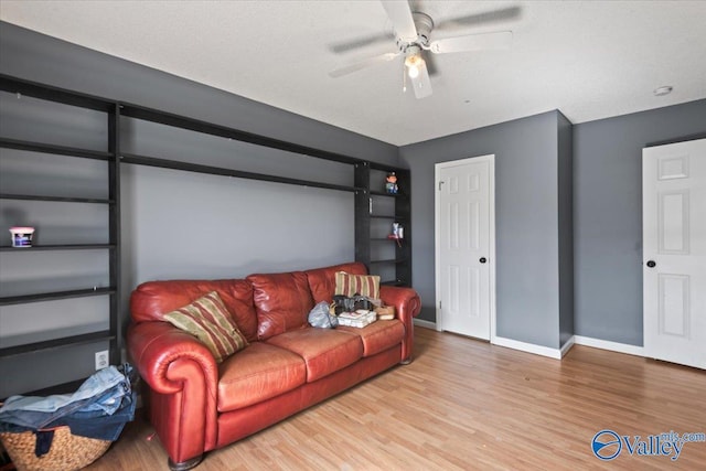 living area featuring light wood-style floors, baseboards, and a ceiling fan