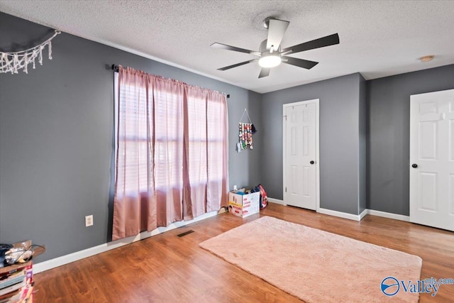 unfurnished bedroom featuring visible vents, baseboards, ceiling fan, wood finished floors, and a textured ceiling