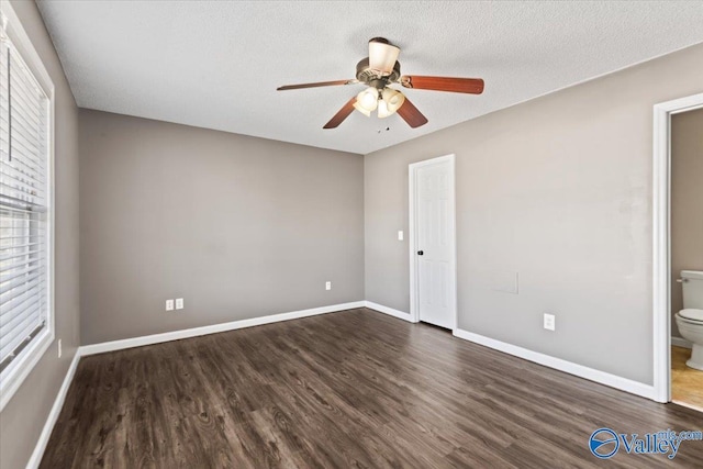 unfurnished bedroom featuring a textured ceiling, baseboards, and dark wood-style flooring