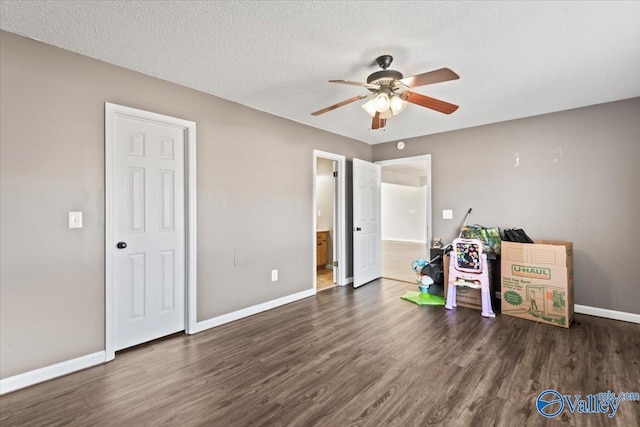 interior space featuring a textured ceiling, baseboards, and dark wood-style flooring