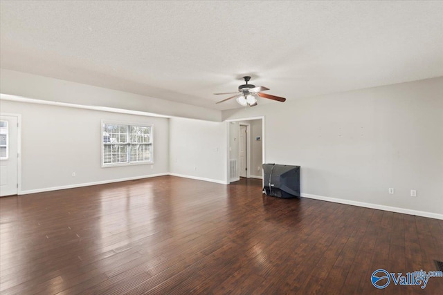 unfurnished living room with a textured ceiling, dark wood finished floors, and baseboards