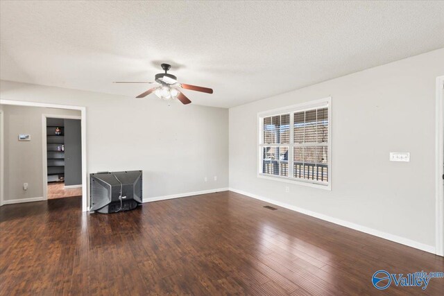 unfurnished room with a textured ceiling, dark wood finished floors, and baseboards